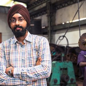 Sikh supervisor at a factory overseeing the workers complete their job in the given time.